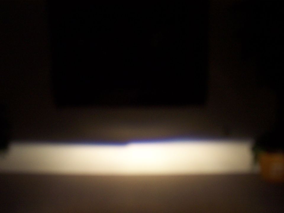 car headlight beam illuminating a surface, with a dark background and a watermark at the bottom right