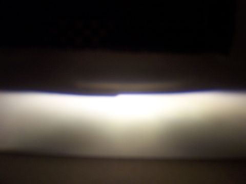 1993 Ford Probe - A bright headlight beam cuts through darkness, creating a stark horizontal line of light.