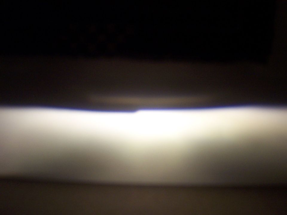 Headlight beam illuminates a dark surface with a bright horizontal band