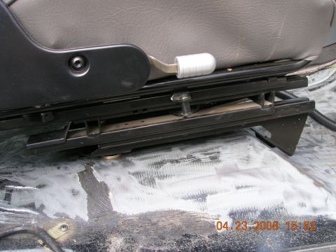 1996 Ford Bronco - The underside of a vehicle seat shows its slider mechanism and mounting points.