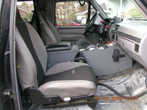 1996 Ford Bronco - The interior of a truck shows custom seats and a modified center console with various controls and equipment.