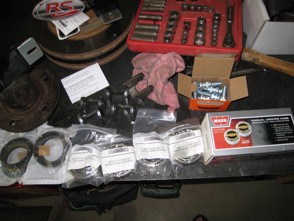Wheel bearings, locking hubs, brake rotor, and socket set on a workbench