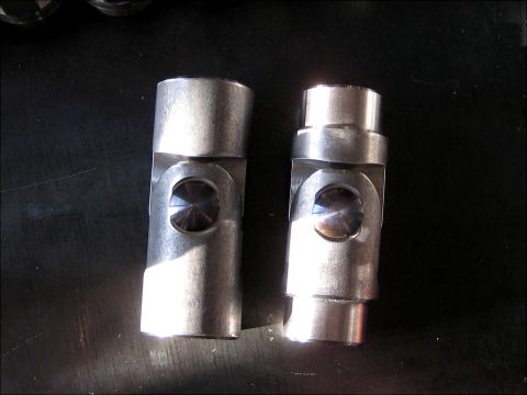 1996 Ford Bronco - Two metal universal joints are shown on a dark surface, with one appearing slightly larger than the other.