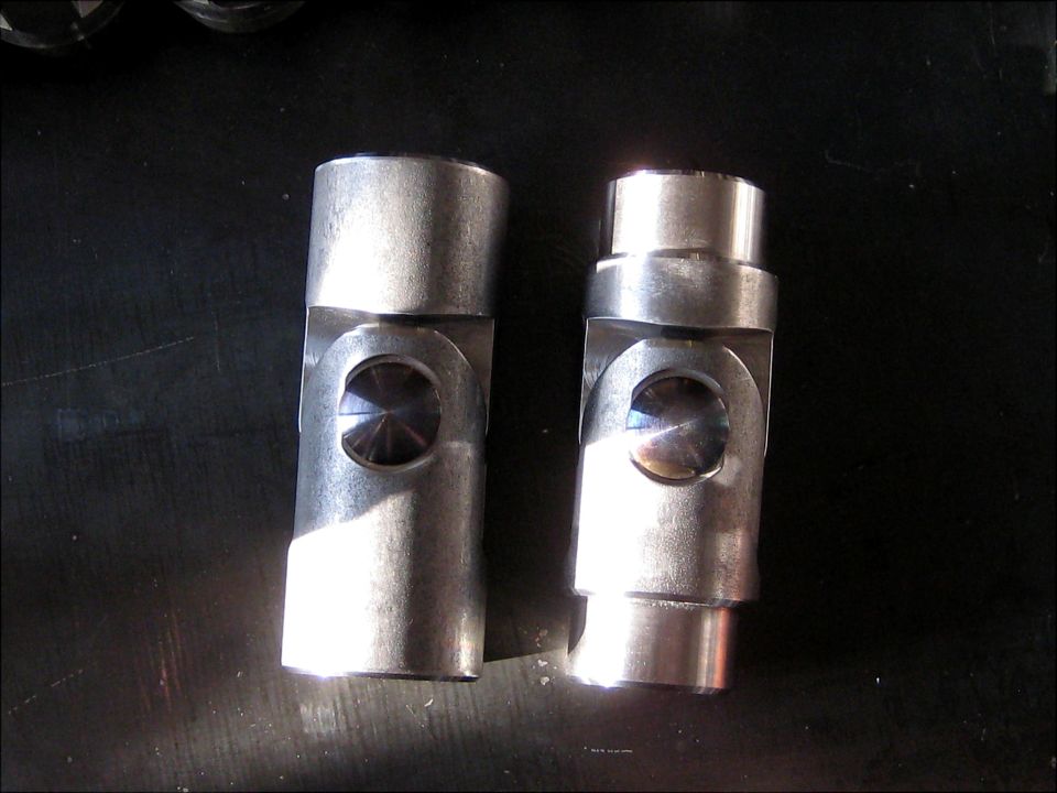 Two metal universal joints side-by-side on a dark surface