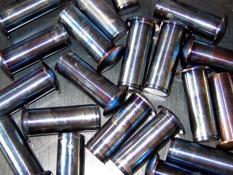 1996 Ford Bronco - A collection of cylindrical metal pins with flared ends are scattered across a flat surface.