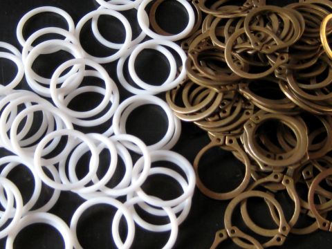 1996 Ford Bronco - A collection of white plastic rings and brass metal rings are scattered on a dark background.