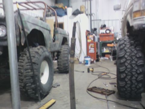 1992 Ford F-350 - An off-road vehicle with oversized tires is parked in a garage, with another vehicle partially visible to the right.