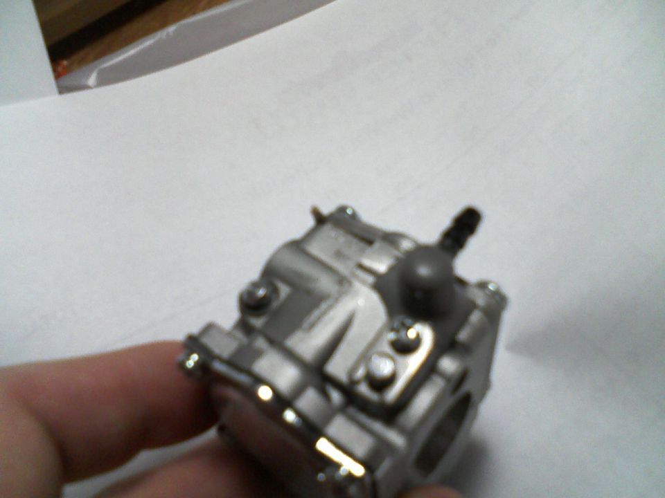 Carburetor held in hand, with Supermotors.net logo in corner