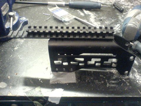 1985 Ford Bronco - A black metal gun accessory rail is shown on a workbench with tools and screws.