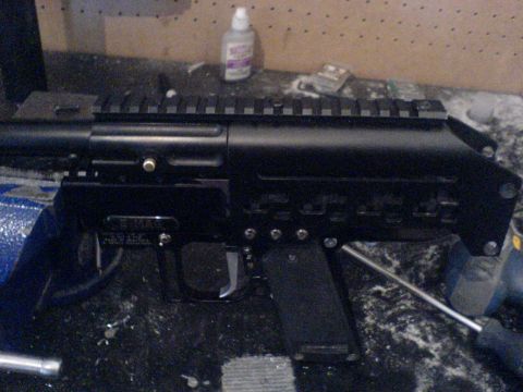 1985 Ford Bronco - A black firearm receiver with a rail system is secured in a vise, with tools and a bottle of adhesive visible in the background.