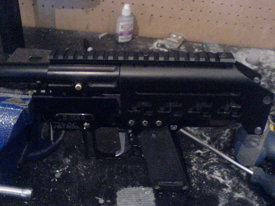 Black firearm receiver with rail system, held in a vise