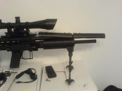 1985 Ford Bronco - A tactical rifle with a scope and bipod is displayed on a table with accessories.