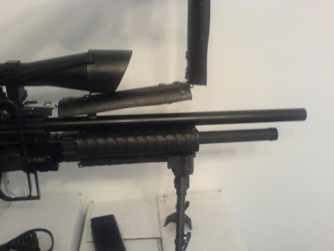 1985 Ford Bronco - Close-up of a rifle scope and barrel assembly, with a bipod extended.