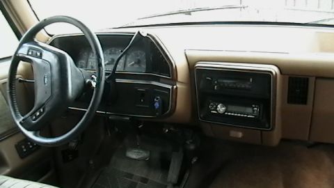 1990 Ford Bronco - The interior of a 1987 Ford F-150 truck, a tan dashboard, steering wheel, and aftermarket radio.