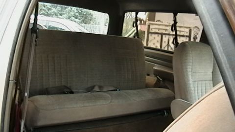 1990 Ford Bronco - The interior of a vehicle shows the rear bench seat and a portion of the passenger seat, with seatbelts fastened.