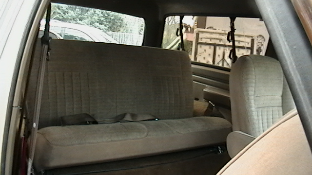 Back seat and passenger seat of a vehicle interior. Seatbelts are visible
