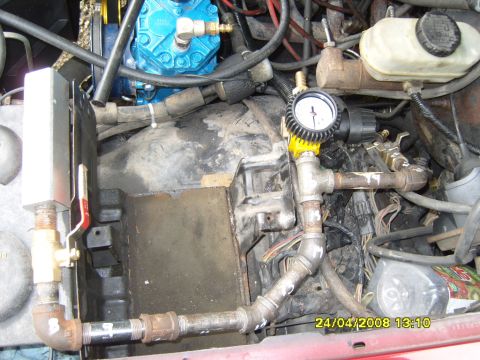 1989 Ford Bronco - Close-up of an engine bay showing a blue compressor and a pressure gauge with plumbing.