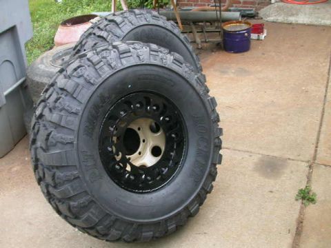 1990 Ford Bronco - A pair of Pit Bull Rocker mud-terrain tires with aggressive lug tread mounted on 8-lug beadlock-style wheels, the front one showing a black…