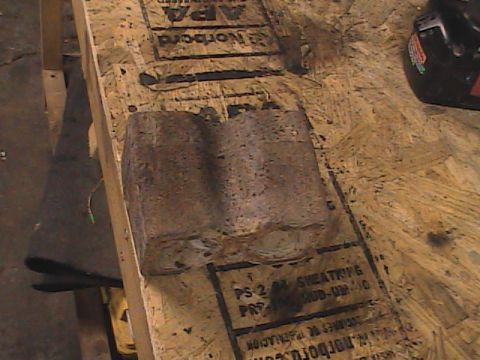 1980 Dodge Magnum - A heavily rusted metal component rests on a piece of plywood, obscuring any potential vehicle identification.