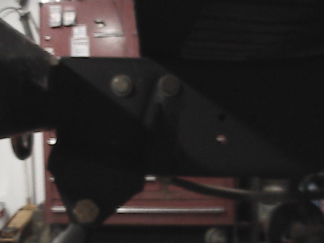 Black metal bracket with bolts, part of a vehicle's suspension