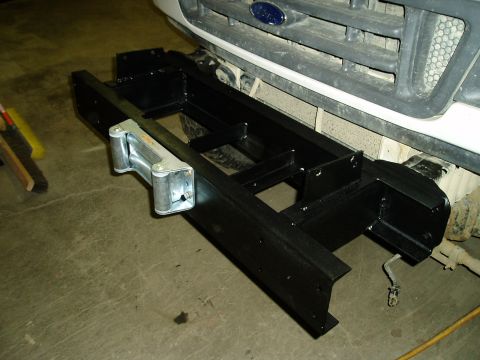 2000 Ford E350 - A black metal bumper assembly with a winch is mounted to the front of a white Ford truck.