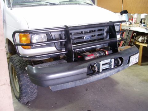 2000 Ford E350 - Front view of a white Ford van with a heavy-duty bumper and winch, parked indoors.