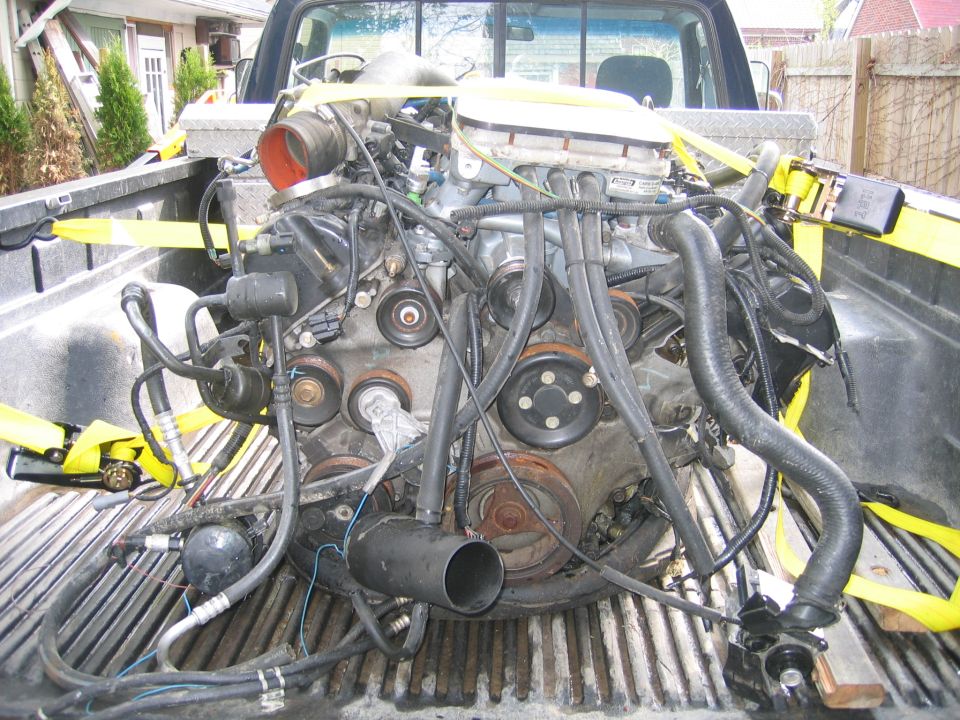 Engine secured with yellow straps in the bed of a pickup truck