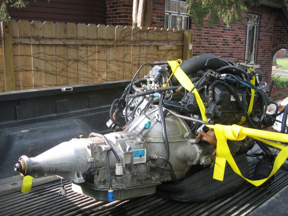 Engine and transmission assembly secured with yellow straps in a pickup truck bed