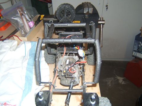 1988 Ford Bronco - RC crawler chassis assembly with motor and suspension components, secured in a vise for work.