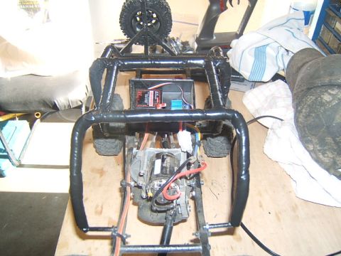 1988 Ford Bronco - RC crawler chassis with motor, battery, and roll cage visible. Spare tire is mounted on top.