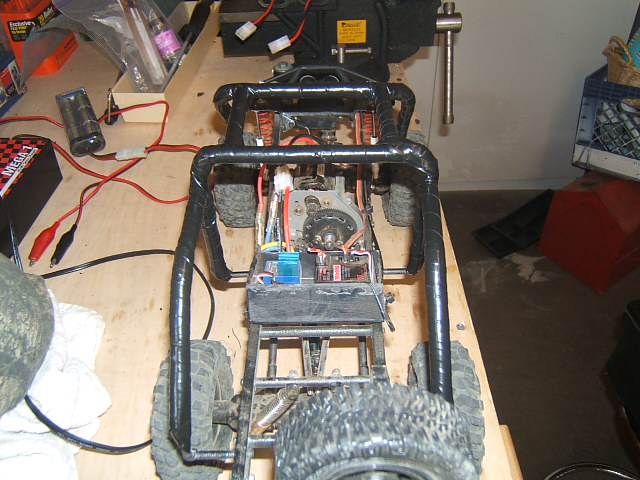 RC buggy chassis with exposed motor, battery, and wiring on a workbench