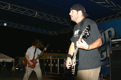 1987 Ford Bronco - Two guitarists perform on stage under bright lights, with equipment cases in the background.