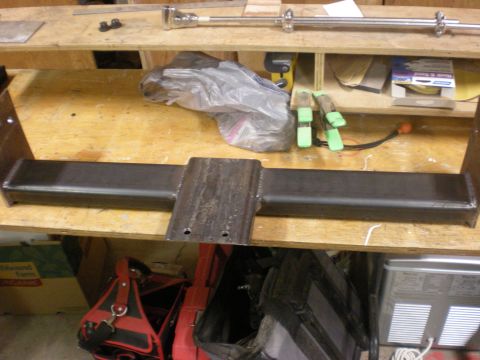 1993 Ford Bronco - A custom metal fabrication part is shown on a workbench, with tools and supplies in the background.
