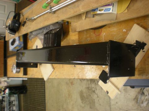 1993 Ford Bronco - A black metal component rests on a workbench, surrounded by various tools and workshop materials.
