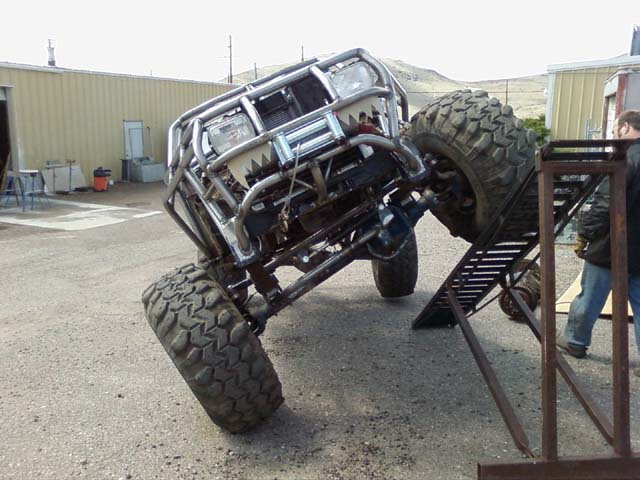 Custom off-road vehicle with large tires on a metal ramp