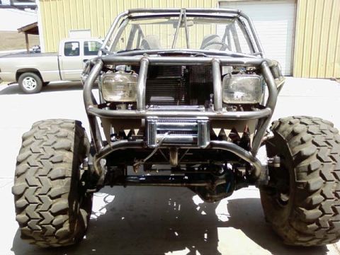 1982 Toyota 4Runner - This heavily modified off-road vehicle is shown from the front, with a second pickup truck visible in the background.