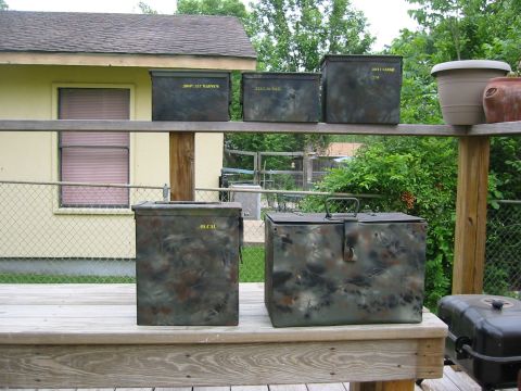 1996 Ford Bronco - Several camouflaged military-style ammo cans are displayed on a wooden deck, with a house and trees in the background.