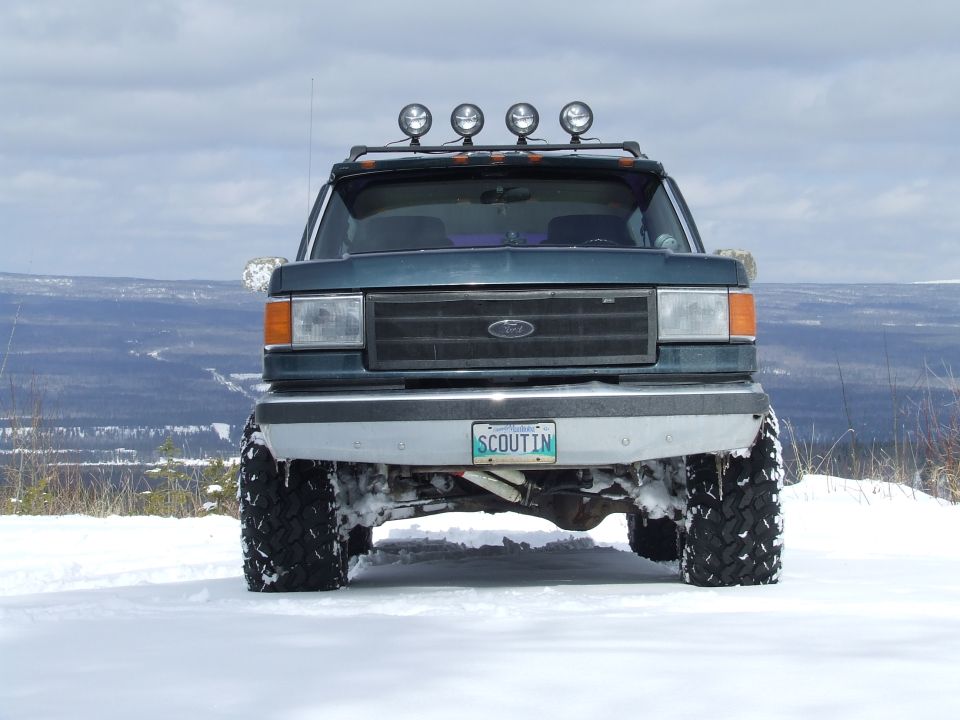 Lifted dark green Ford Bronco head-on in snow with roof light bar and SCOUTIN plate