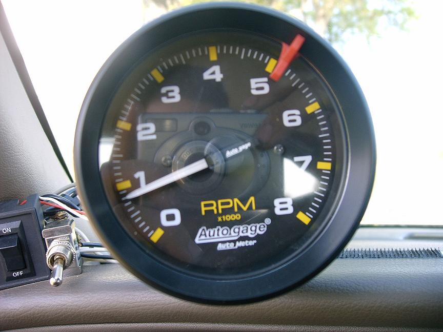 Auto Gage tachometer with RPM markings and a needle pointing to 5
