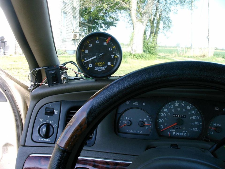 Tachometer mounted on the dash next to the steering wheel. Dashboard gauges and controls are visible