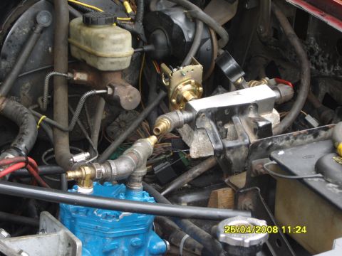 1989 Ford Bronco - Cluttered engine bay detail of an in-progress on-board air setup: a blue-painted York-style piston compressor plumbed with brass fittings,…