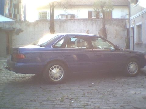 1995 Ford Taurus - Side profile of a blue 1995 Ford Taurus sedan parked outdoors.