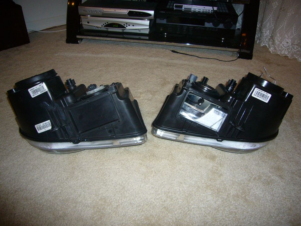 Pair of automotive headlight assemblies on carpet showing housings and reflectors