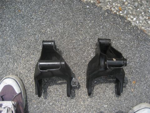 1993 Ford Probe - Two suspension control arms are shown on a paved surface, with a shoe visible to the left.