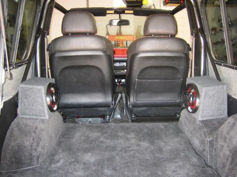 1987 Suzuki Samurai - Aftermarket subwoofers installed in the rear cargo area of a vehicle, flanking the seats.