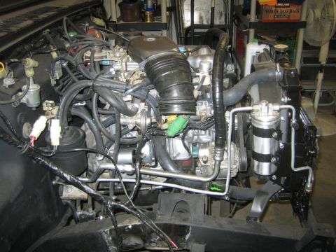 1987 Suzuki Samurai - Close-up view of the engine bay, showing various hoses, wiring, and engine components.