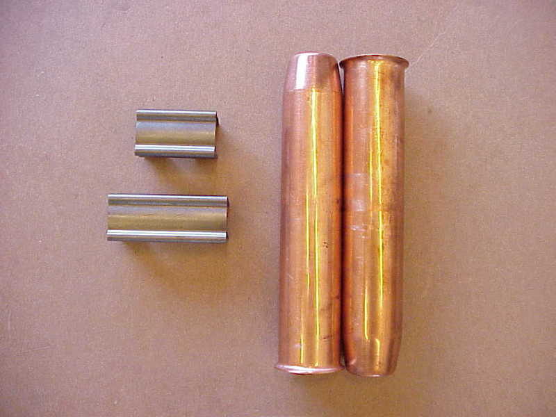 Two steel wrist pins beside two flared copper tubes laid on brown paper