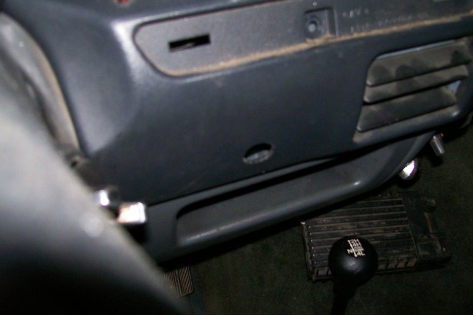 Vehicle interior lower dash with gray trim, floor pedal, and black gear shifter knob