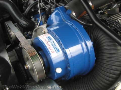 1968 Ford Mustang - Close-up view of a supercharger installed in a vehicle's engine bay.