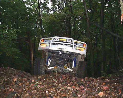 1988 Ford Bronco - This 1988 Ford Bronco navigates a rocky trail, its off-road capabilities with a prominent brush guard.